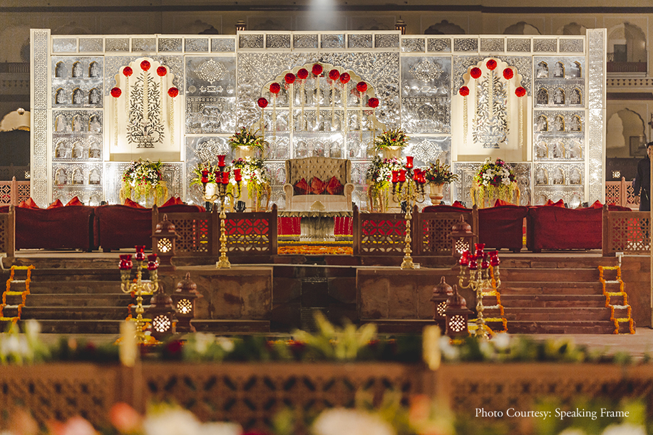 Royal Traditional Palace themed with fairy lights, red drapes and vivid blooms Wedding decoration at Jai Mahal Palace, Jaipur