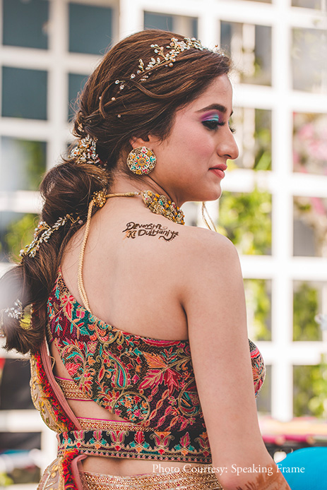 Bride wearing pink one-shoulder lehenga with jewelry by Qbik