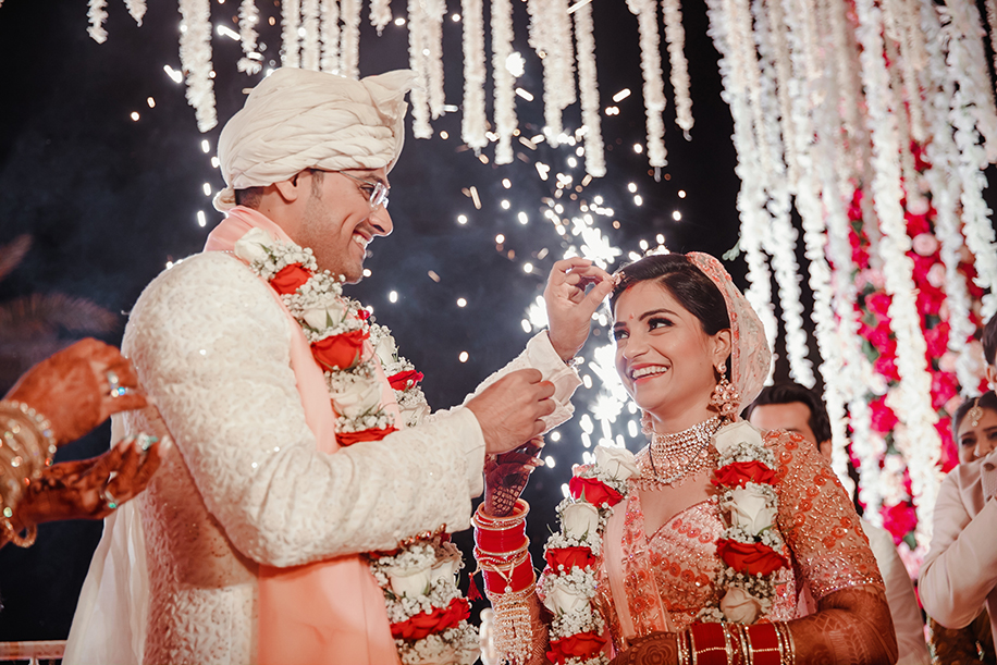 Bride wearing white and pink embroidered lehenga and groom wearing a white sequined sherwani and turban
