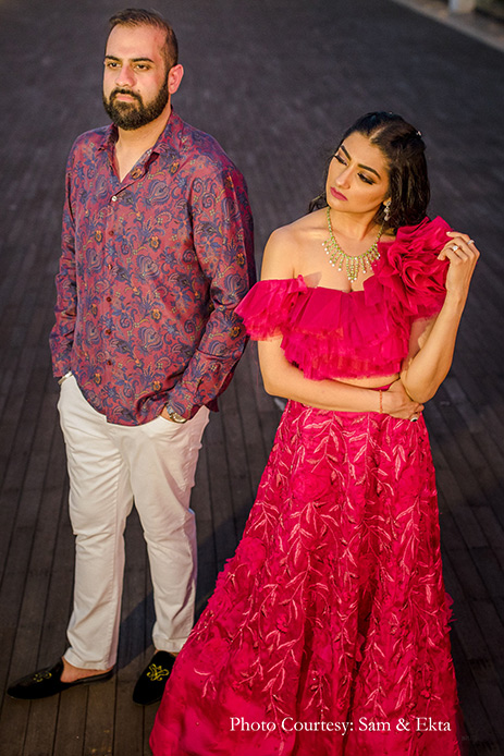 Bride in Hot pink ruffled crop top and skirt by Shriya Som and groom wearing purple printed shirt and white pant by Etro