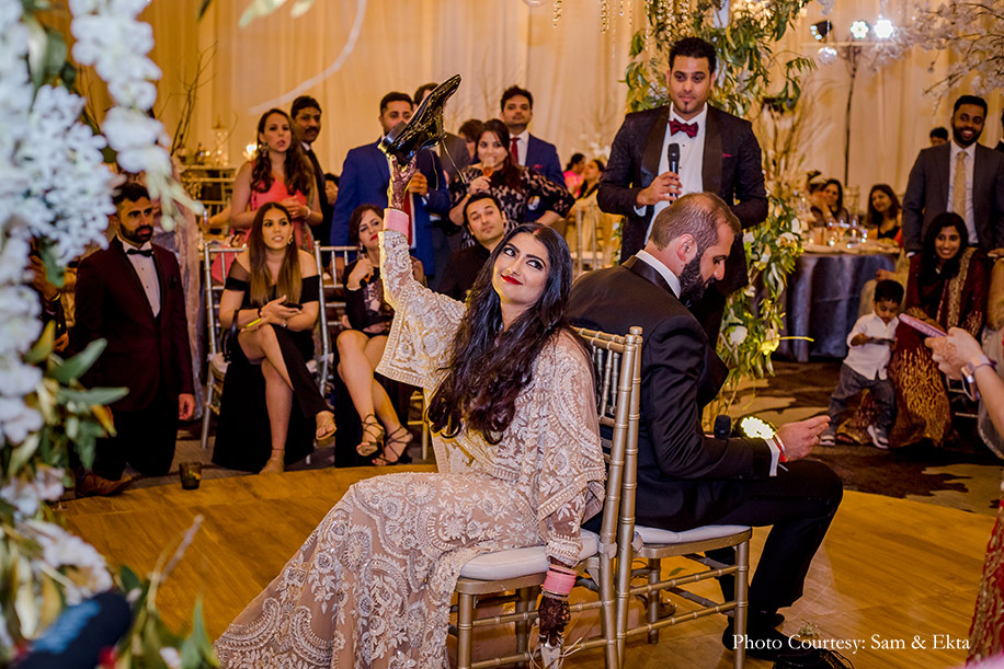 Bride wearing Ivory and white gown by Sabyasachi and groom wearing black tuxedo for reception