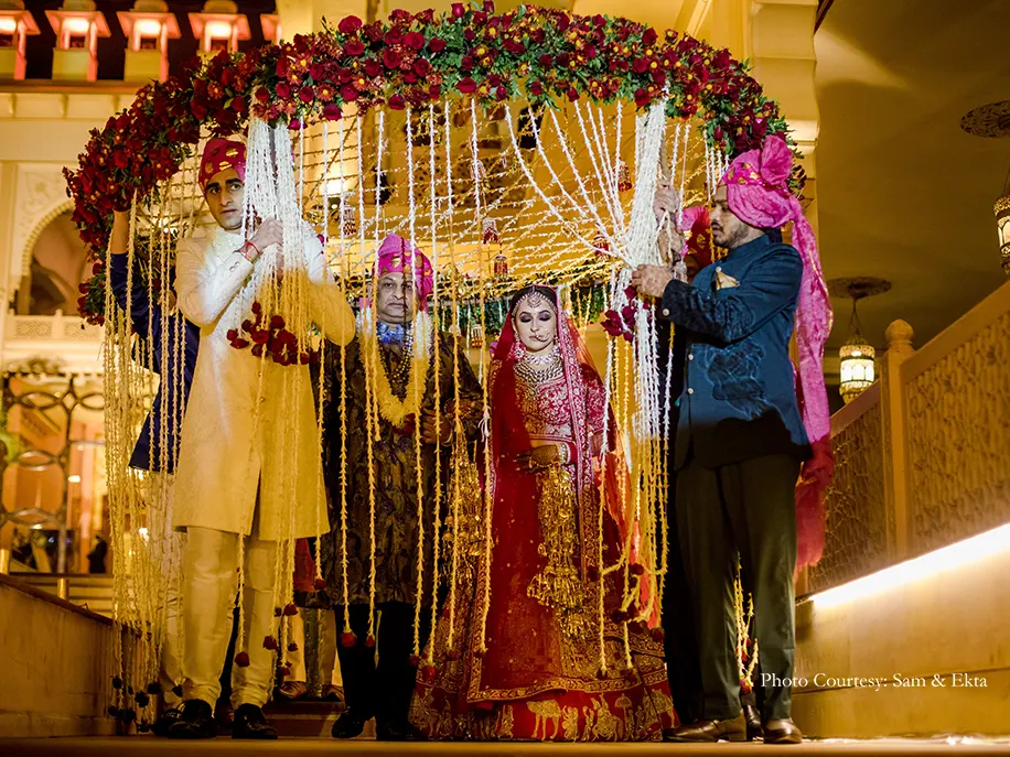 Bride wearing red lehenga and groom wearing white sherwani for the wedding