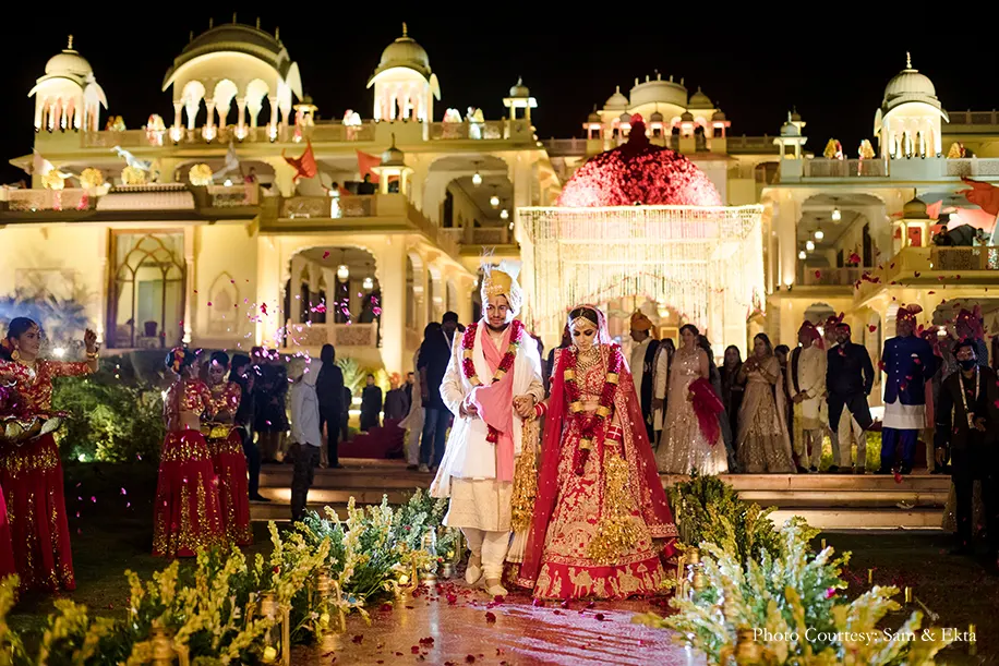 Bride wearing red lehenga and groom wearing white sherwani for the wedding