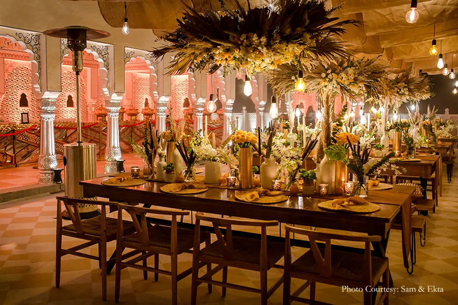 Earthy, boho-chic décor including cane furniture, pampas grass, flowers and foliage with a warm lighting from vintage Edison bulbs, lamps and candles for Welcome dinner