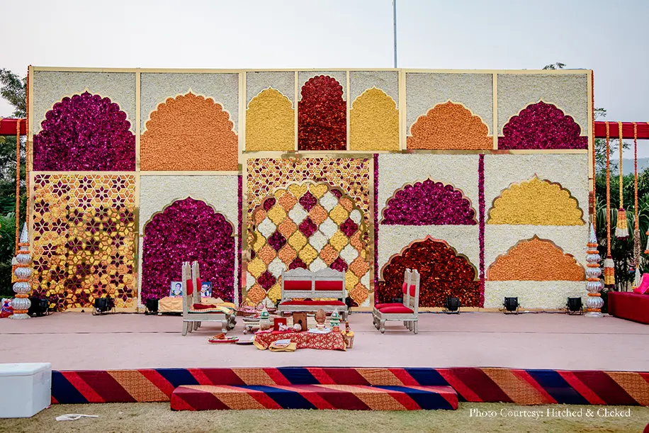 Wedding decor in rich traditional hues of red, white and gold with flowers, candles and diyas
