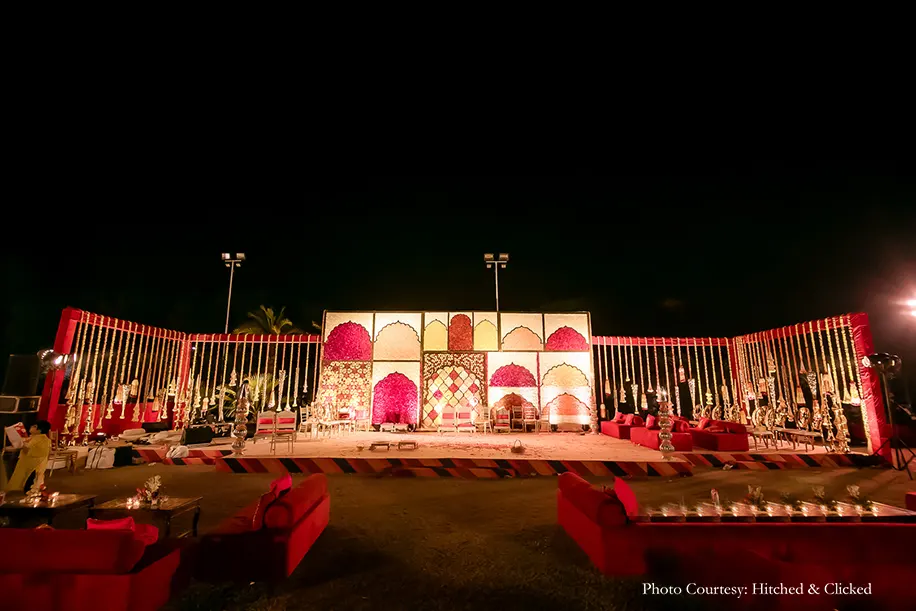 Wedding decor in rich traditional hues of red, white and gold with flowers, candles and diyas