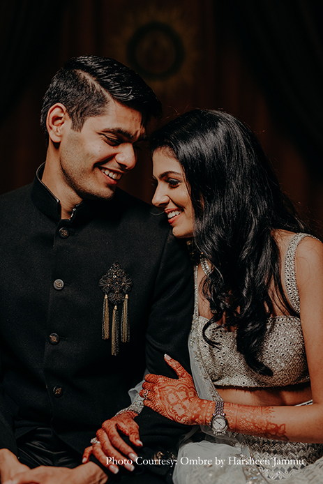 bride in silver embroidery sangeet lehenga and groom in black velvet bandhgala and black trousers