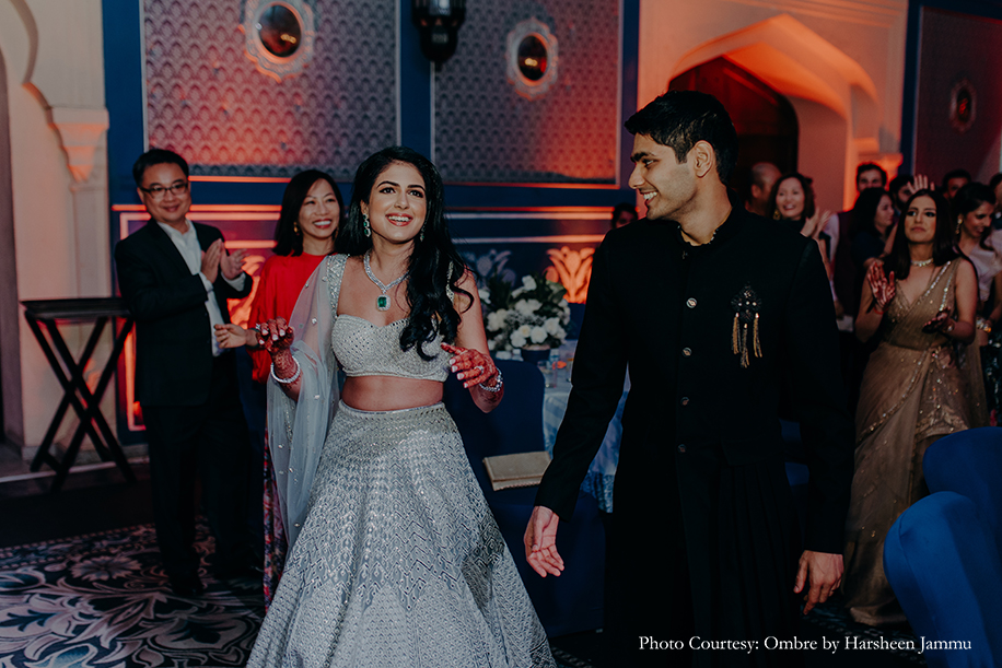bride in silver embroidery sangeet lehenga and groom in black velvet bandhgala and black trousers