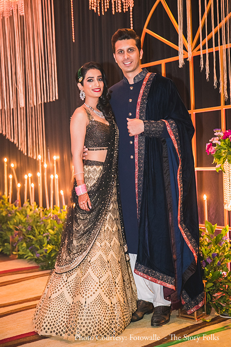 Bride in black and gold sequin lehenga by  Tarun Tahiliani and Groom in navy blue sherwani with a velvet shawl by Megaan