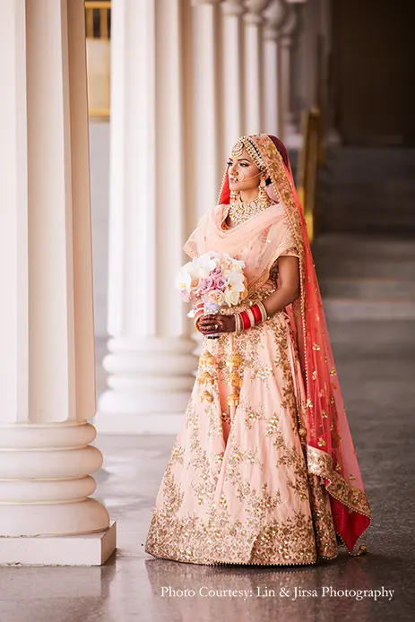 Bride wearing peach lehenga and kundan jewelry