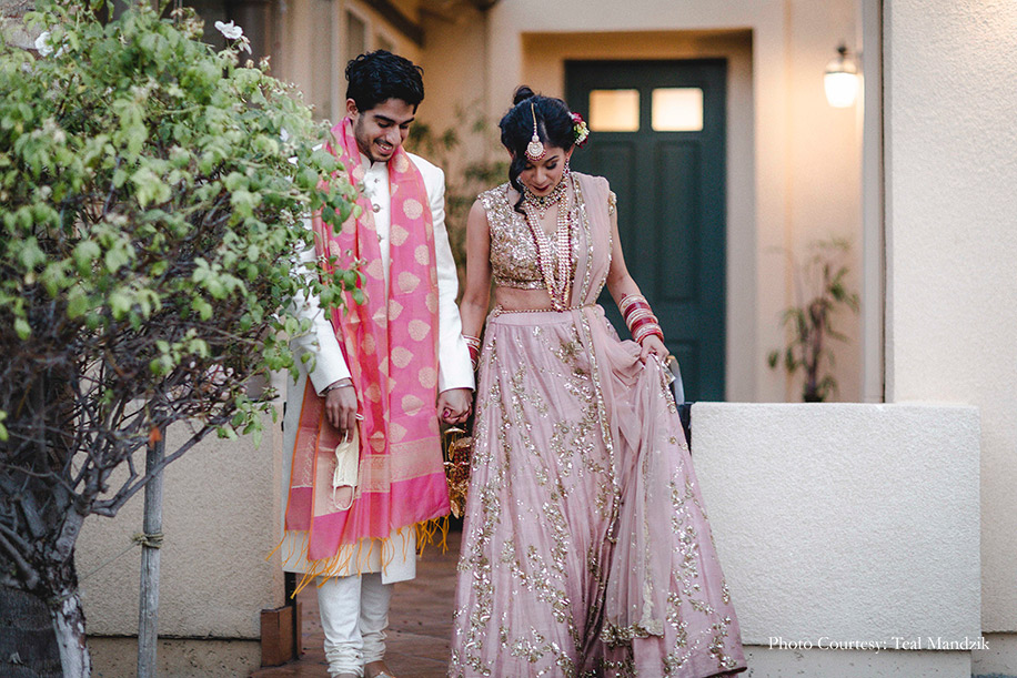 Bride wearing champagne pink lehenga by Astha Narang and Groom in an ivory and pink Sabyasachi Mukherjee for the wedding