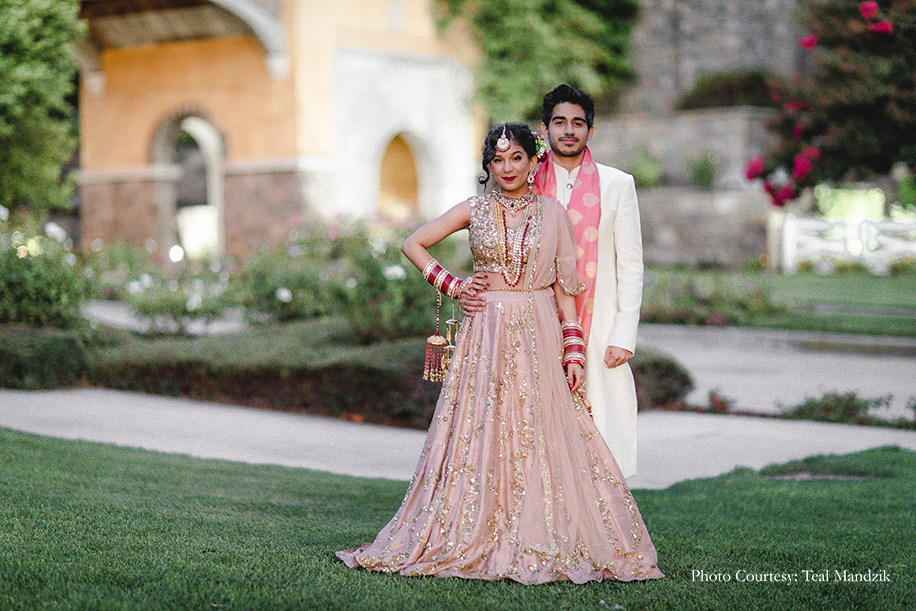 Bride wearing champagne pink lehenga by Astha Narang and Groom in an ivory and pink Sabyasachi Mukherjee for the wedding