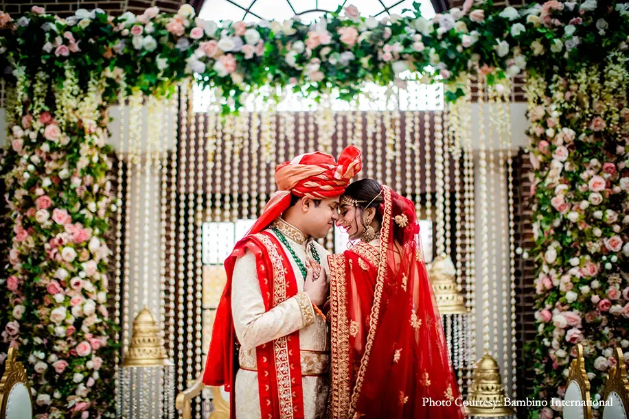 Bride wearing red lehenga and groom in cearm sherwani and red dupatta and safa
