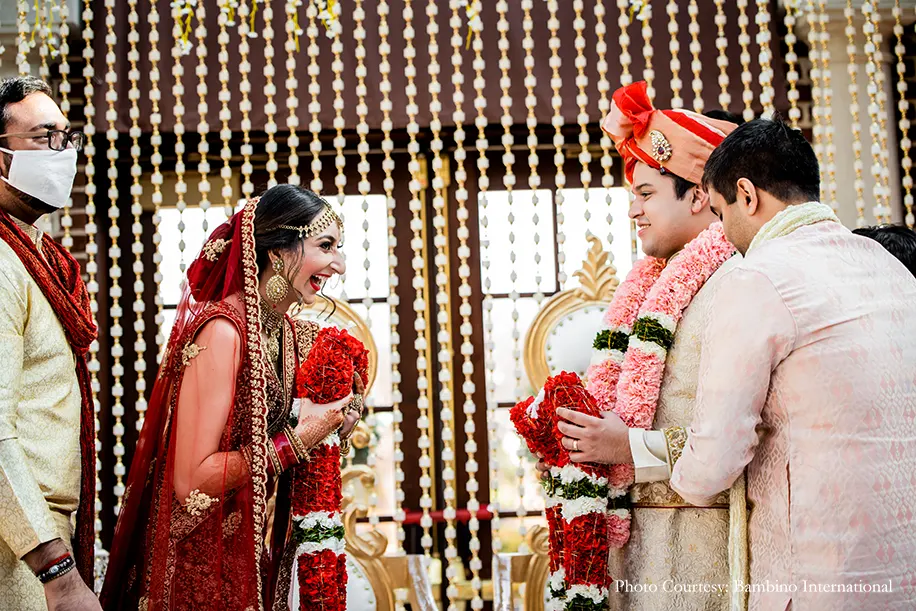 Bride wearing red lehenga and groom in cearm sherwani and red dupatta and safa for the wedding