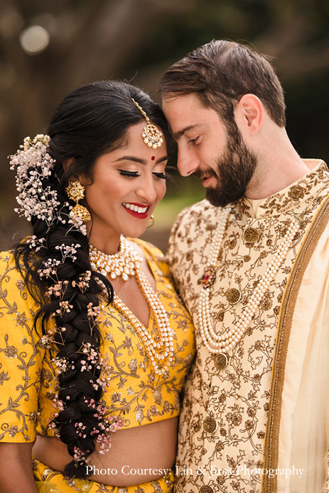 Bride wearing mustard yellow lehenga and groom wearing beige sherwani for the wedding at USA