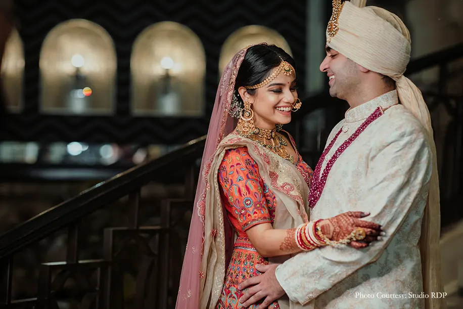 Bride wearing multicolored lehenga and groom wearing off-white sherwani for the wedding