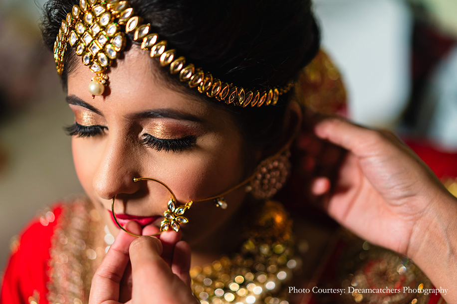 Bride wearing red lehenga by Kalki Fashions with Kundan jewelry