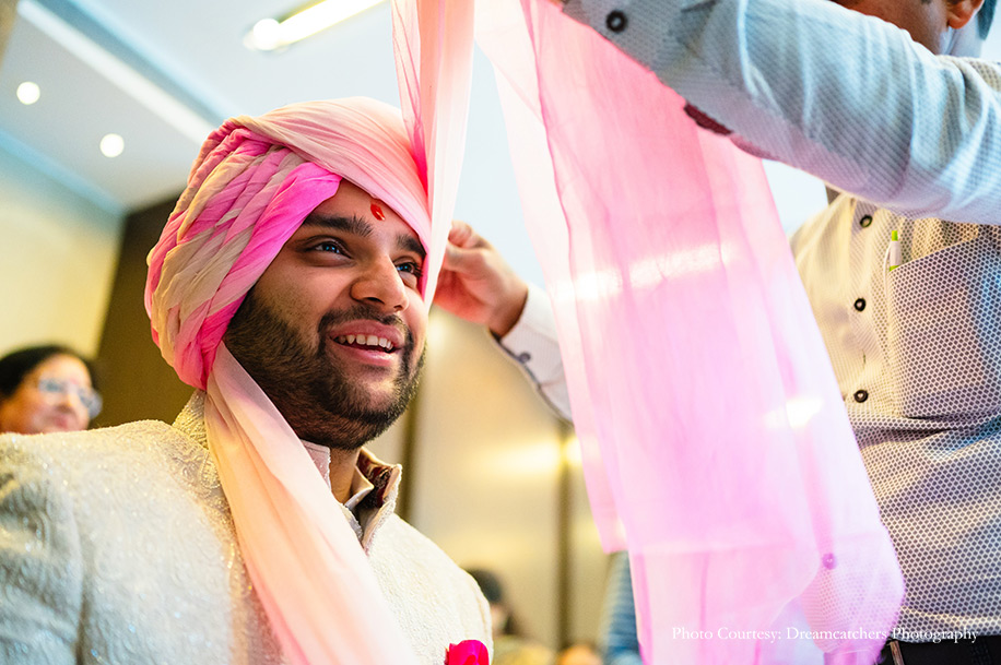 Groom in and groom wearing ivory sherwani with pink safa