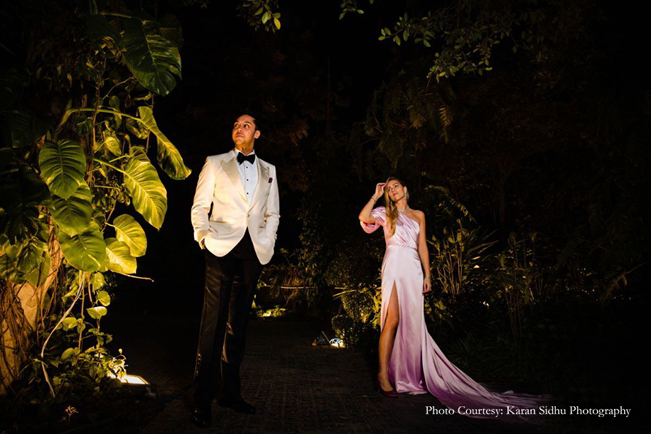 Bride in pink gown and groom in black and white tuxedo for sangeet