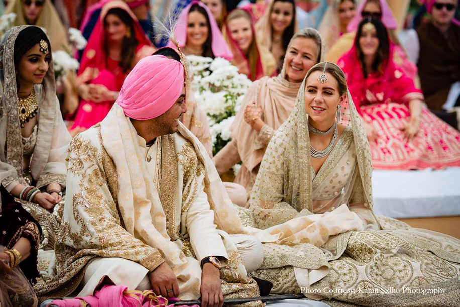 Bride in ivory lehenga and groom in off-white sherwani with gold dupatta by Sabyasachi