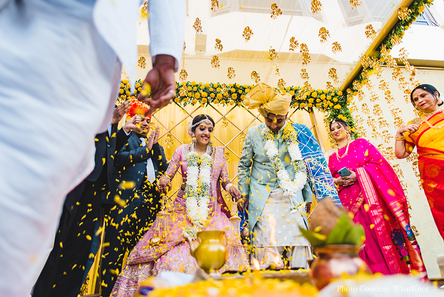 Bride wearing onion pink lehenga by Neeta Lulla with gold motifs, pearls, and sequins work, and the groom donned a soft pearl-blue sherwani