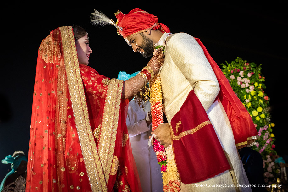 Bride in red lehenga and groom in off-white sherwani by Sabyasachi at ITC Grand Bharat, Gurugram