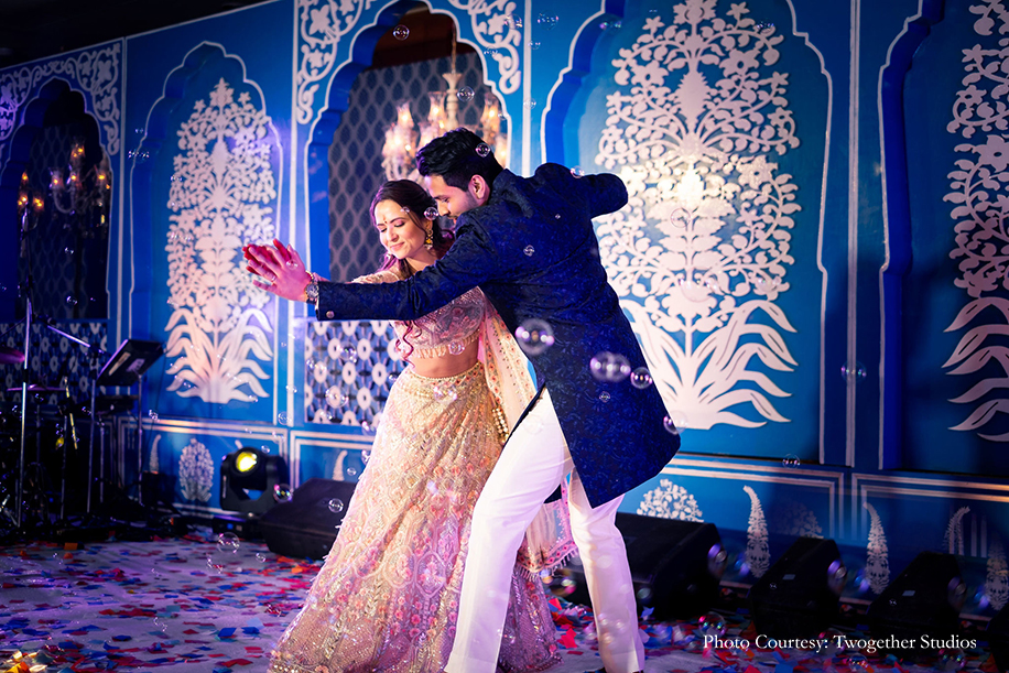Bride in a beige embroidered lehenga with pastel peach and blue accentsand groom wearing blue bandhgala that he accessorized with a pink pocket square
