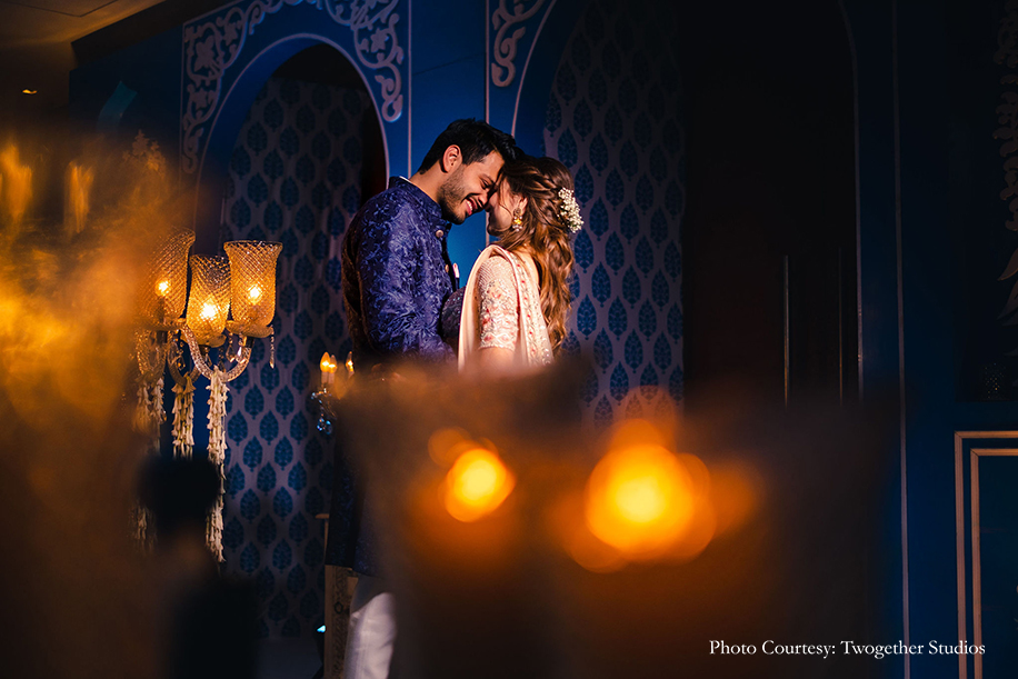 Bride in a beige embroidered lehenga with pastel peach and blue accentsand groom wearing blue bandhgala that he accessorized with a pink pocket square