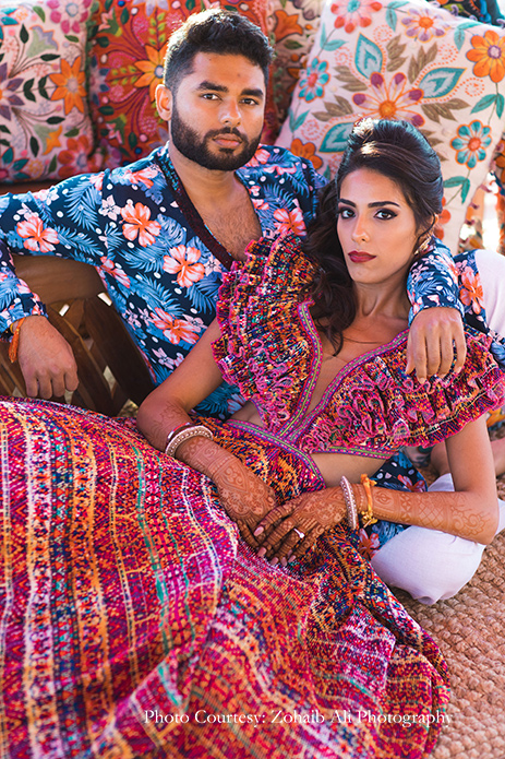 The bride in a ruffled skirt and top in bright pink by Shantanu and Nikhil, and groom in tropical kurta by Study by Janak for The Grand Fiesta at Los Cabos, Mexico