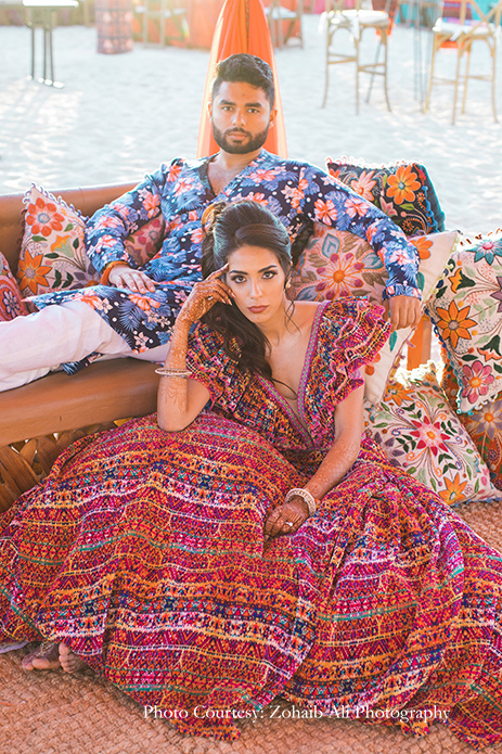The bride in a ruffled skirt and top in bright pink by Shantanu and Nikhil, and groom in tropical kurta by Study by Janak for The Grand Fiesta at Los Cabos, Mexico