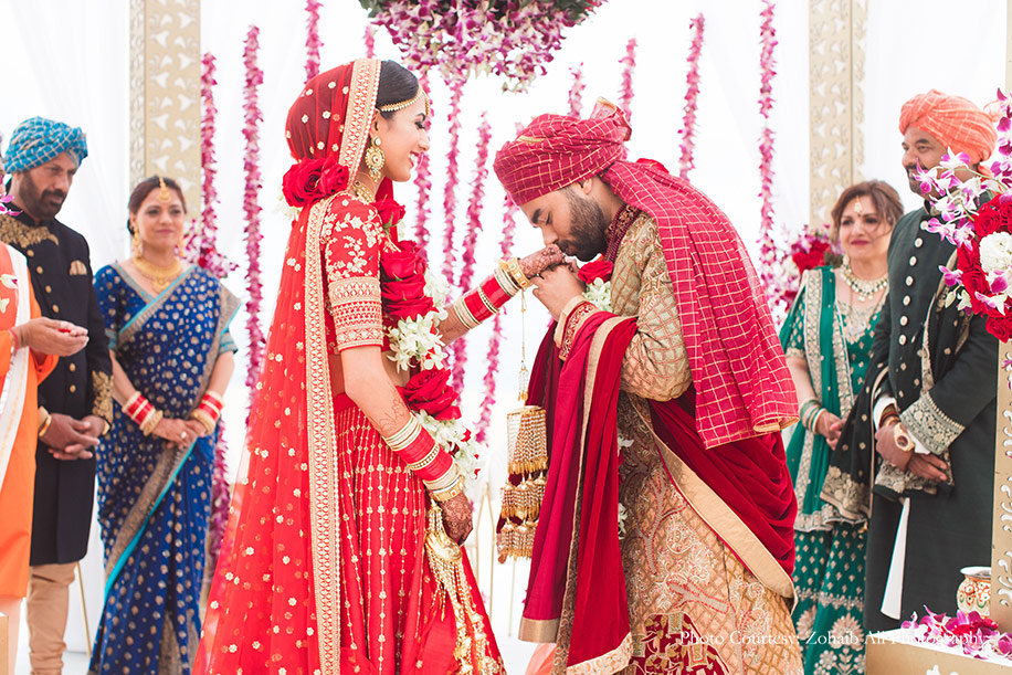 Bride in Red Sabyasachi lehenga with chooda and Kaleere and Groom wearing red and gold sherwani for wedding