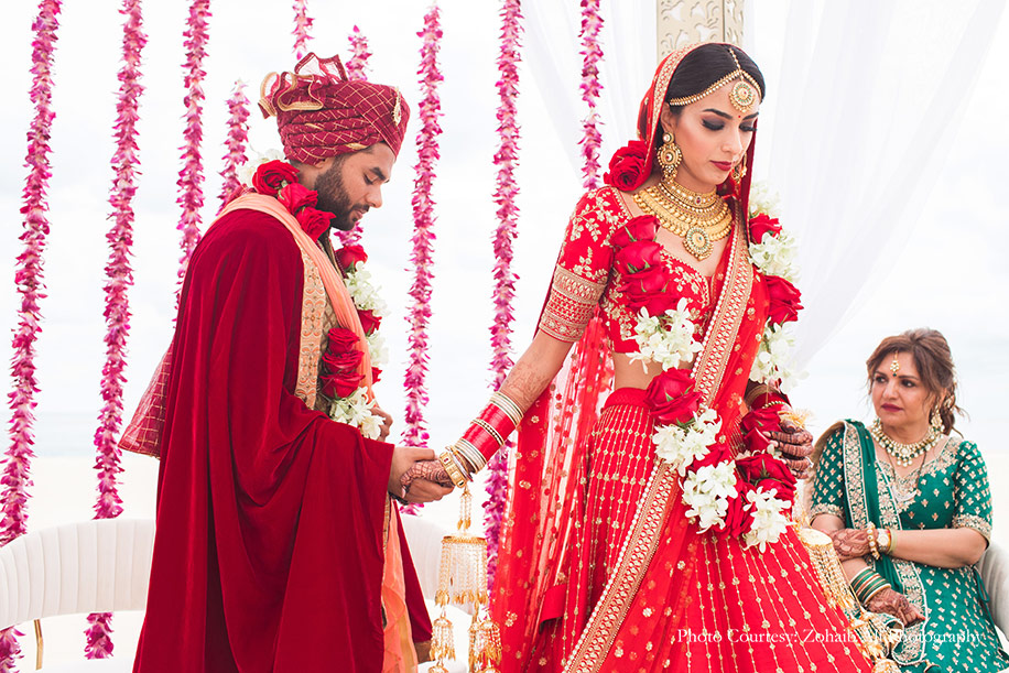 Bride in Red Sabyasachi lehenga with chooda and Kaleere and Groom wearing red and gold sherwani for wedding