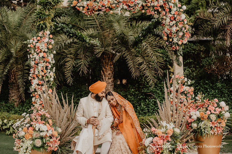 Bride in orange Ushnak lehenga and groom in ivory sherwani with an orange turban by Mr. Fox for the wedding at Amaanta Farms