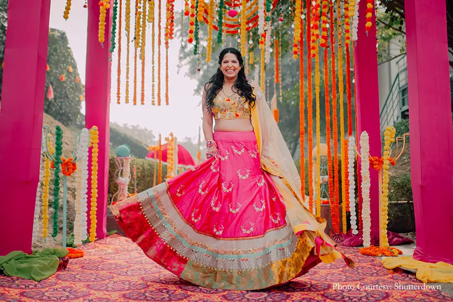 Bride wearing fuchsia and yellow lehenga for Mehndi