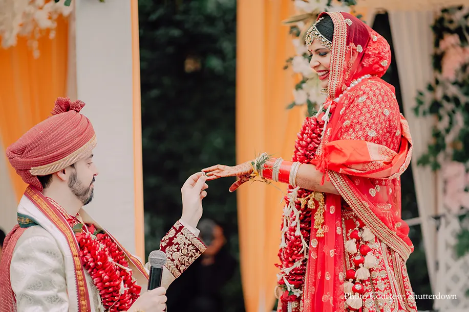 Bride wearing red lehnga and groom wearing white and maroon sherwani for the wedding