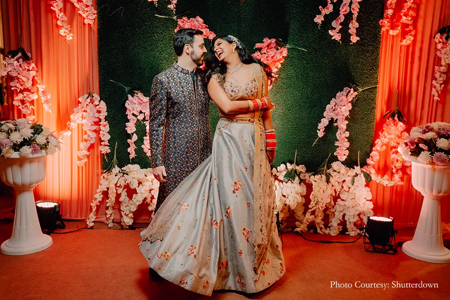 Bride in grey lehnga and groom wearing blue sherwani for the reception