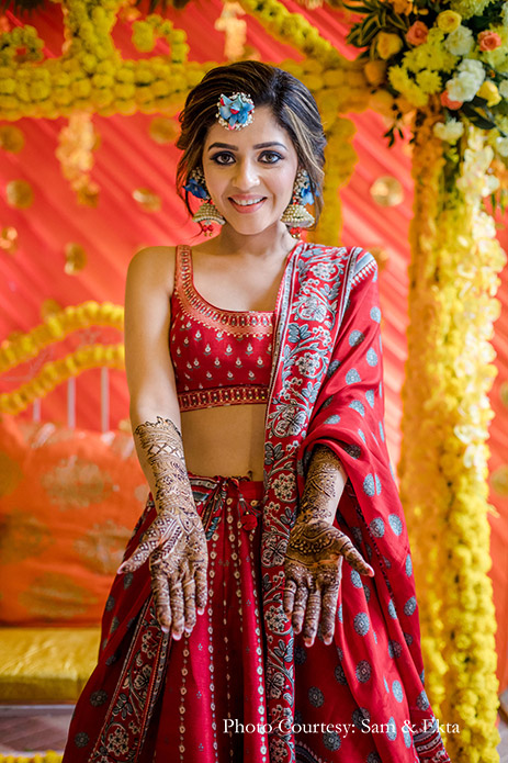 bride wore an Anita Dongre red and blue lehenga, accessorizing it with fresh floral jewelry in a soft braid decked with baby’s breath and blue butterflies