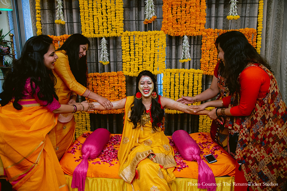 Yellow and orange haldi outfit for Gujrati ‘pithi’ ceremony with floral decor