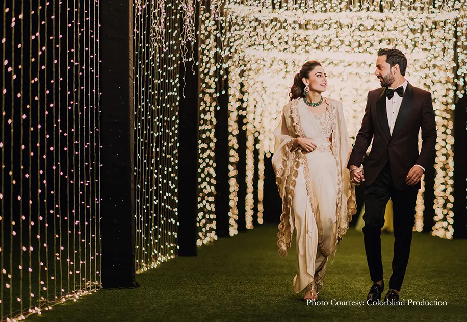 Bride wearing off-white drapped saree and groom wearing tuxedo for the engagement