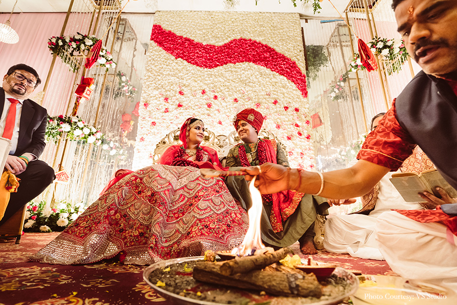 Bride wearing orange lehenga and groom wearing olive green sherwani for wedding