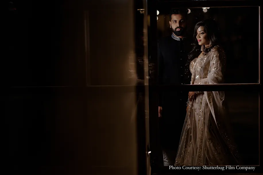 Bride in gold lehenga and groom in black sherwani by Manyavar for the reception