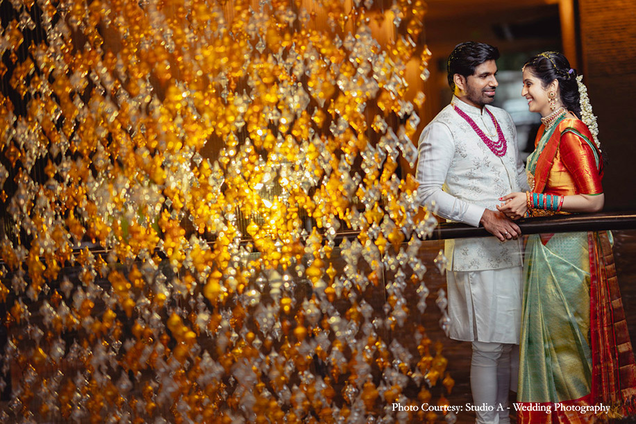 Bride wearing green and orange kanjeewaram and groom wearing white nehru jacket for engagement