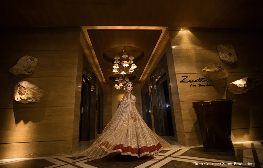 Bride in a cape lehenga by Falguni and Shane Peacock teamed with stunning jewelry and head gear for the sagan
