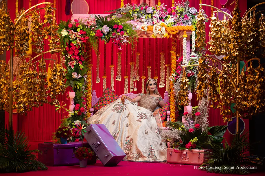 Floral mehendi décor against the bridal swing seating composed of flowers, gold hangings and colorful trunks