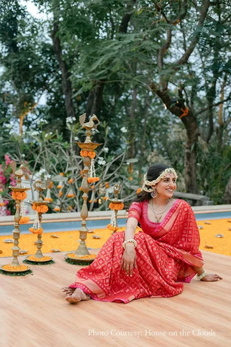 Bride wearing red silk saree and floral jewelry for the poolside function