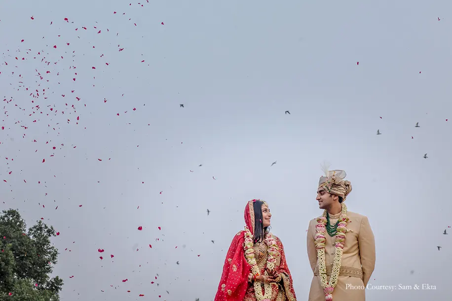 Bride in Gold multi-colored lehenga by Rimple and Harpreet Narula with Red Bandni dupatta and Kundan jewelry and groom wearing beige sherwani with tarban