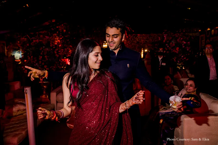Bride wearing Maroon Sabyasachi saree and groom wearing Black Bandh-gala for the reception
