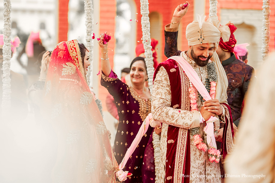 Bride in red lehenga by Mongas and Groom in off-white sherwani by Sabyasachi