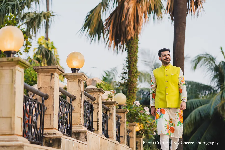 Groom wearing floral kurta set with a sunny yellow Bandi by Sabyasachi for the Mehndi at Taj Lands end