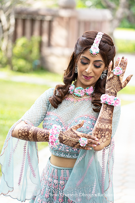 Bride in a teal blue and pink lehenga with floral jewelry for her mehendi